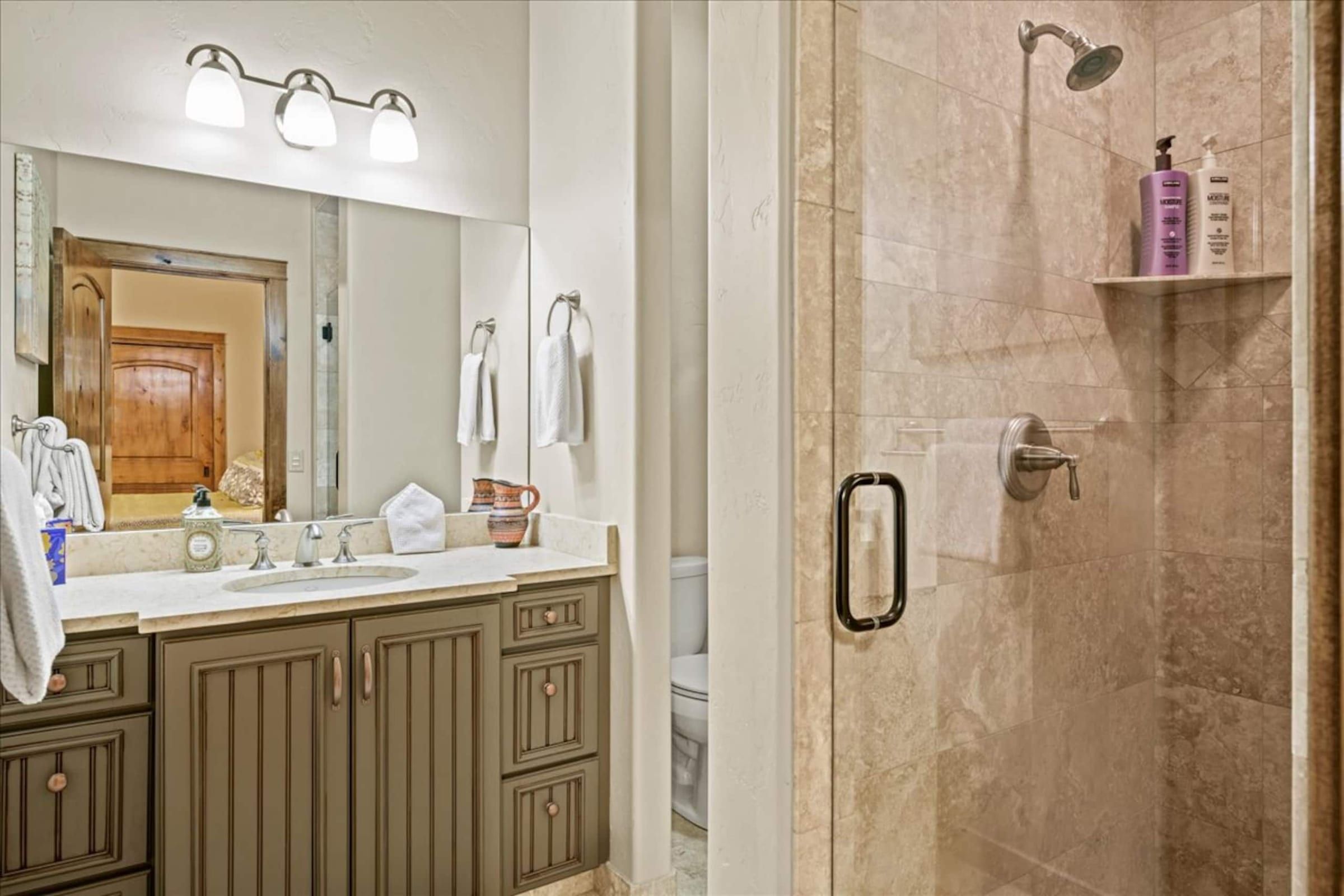The ensuite with a tiled walk-in shower and a single vanity