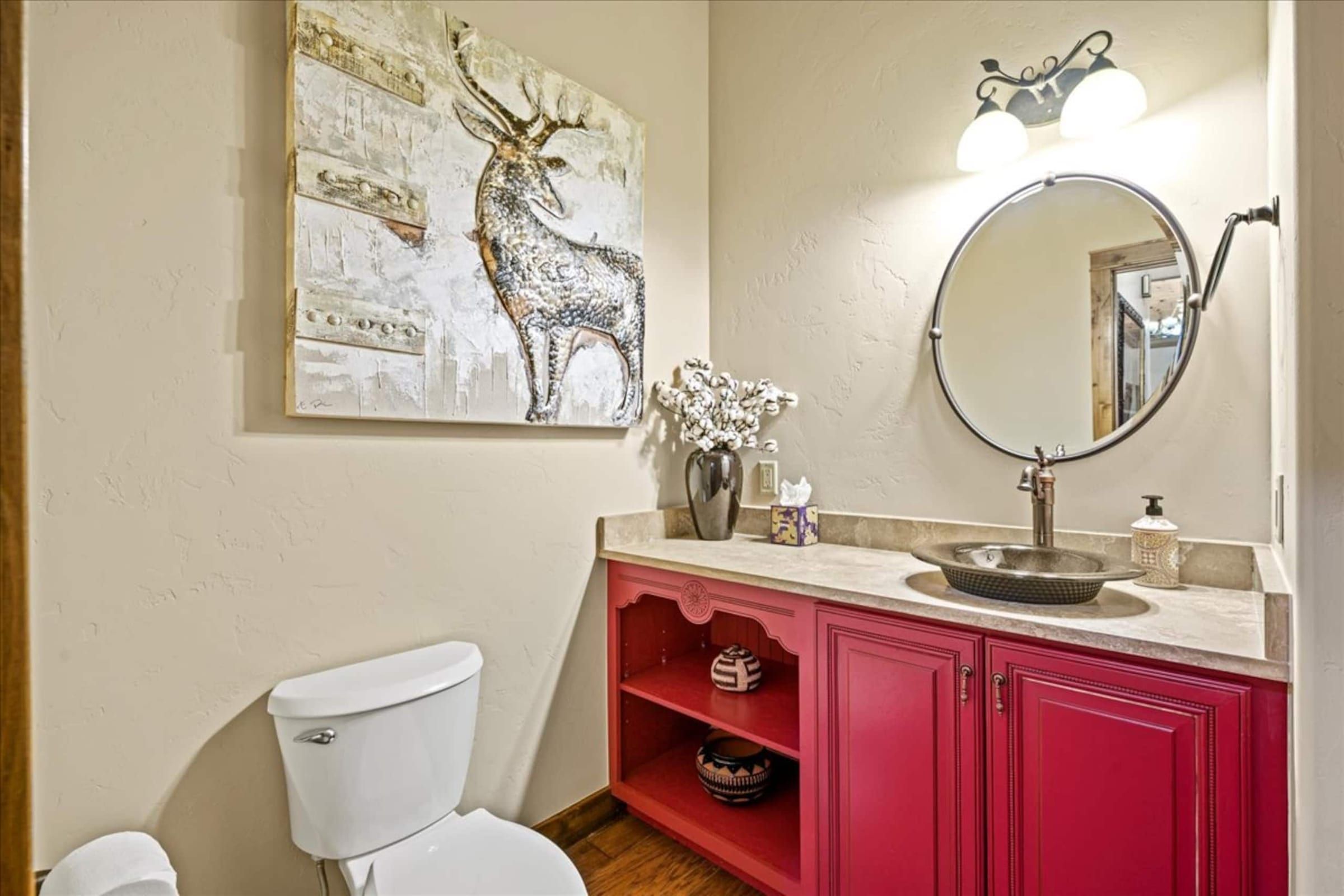 The half bath: a red vanity, an elk print and a round mirror