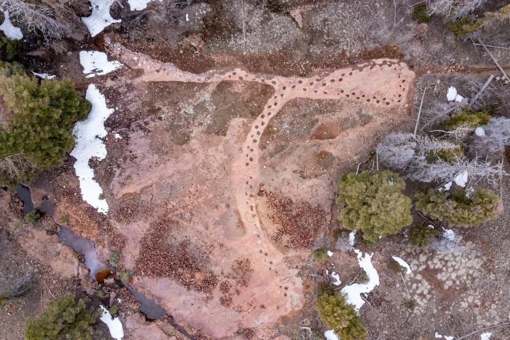 An aerial view of the dinosaur trackway, a looping line of footprints across red sandstone