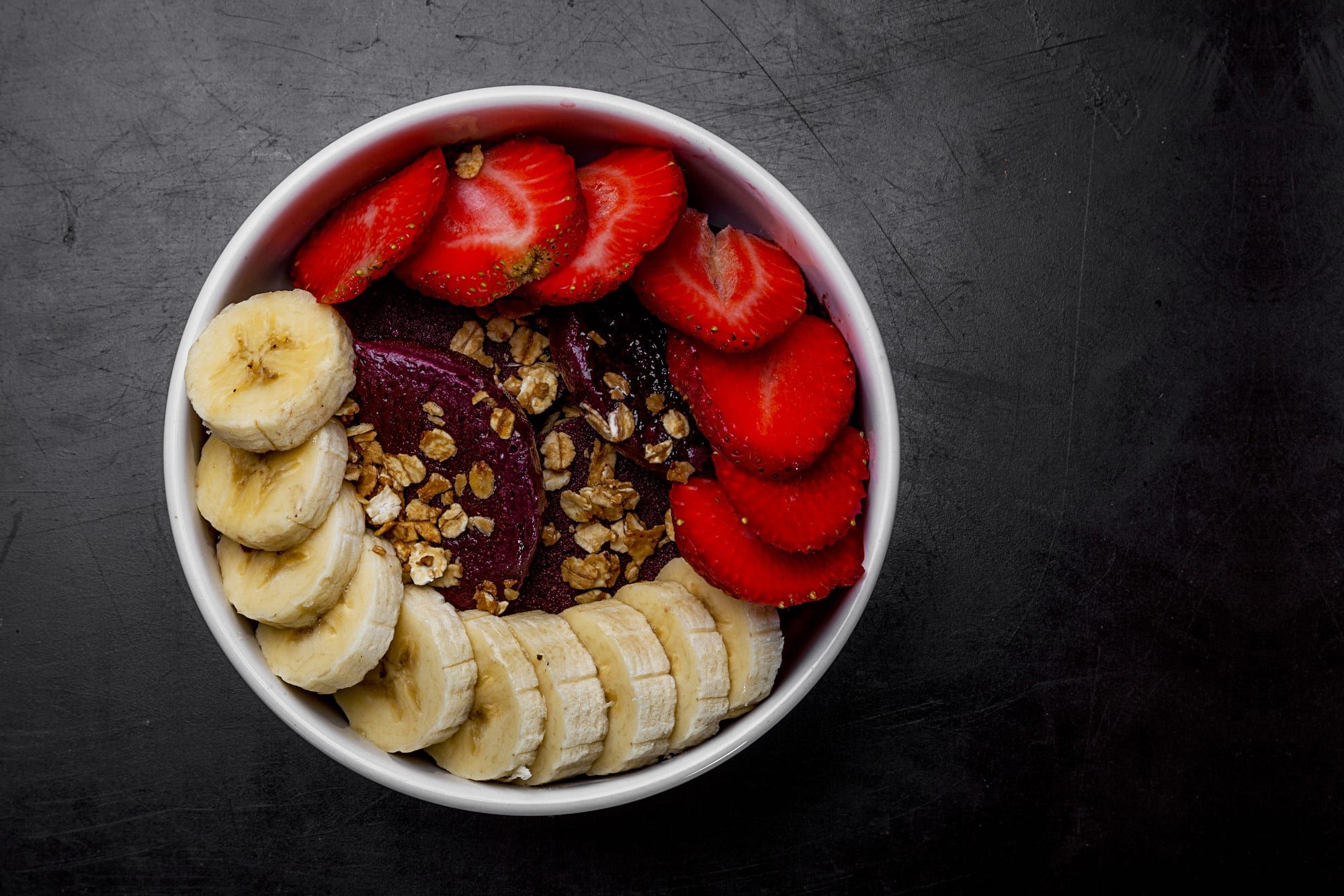 An açaí bowl topped with strawberries, banana and granola