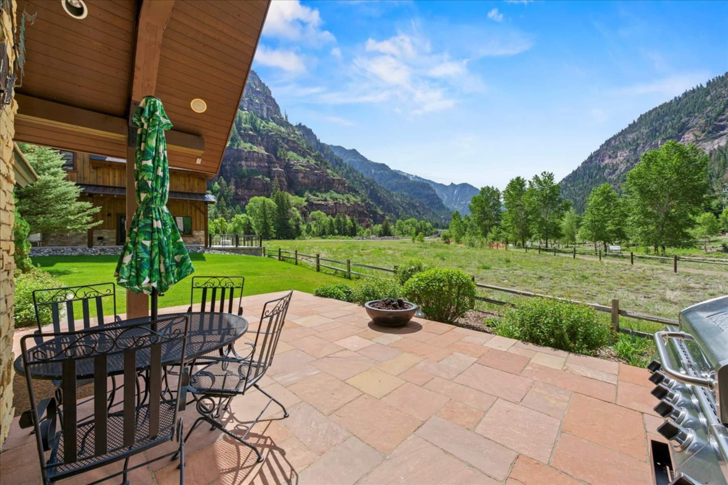 The back flagstone patio with a dining table, grill and canyon view